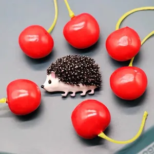 Detailed close-up of a cute hedgehog enamel brooch with 3D embossed texture and cherries