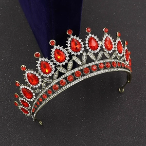 Close-up of Baroque gold bridal crown with red teardrop gems on blue velvet
