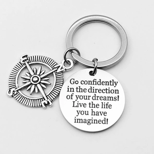 Detail of compass charm and engraved stainless steel keychain with motivational quote