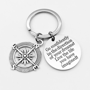 Detail of silver compass keychain with engraved Drive Safely message and metal charm