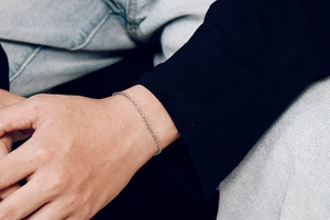 Minimalist silver steel chain bracelet shown on a wrist with casual denim background
