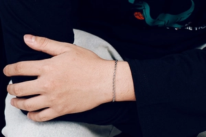 Detailed view of silver stainless steel chain bracelet worn on wrist for a minimalist look