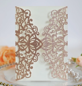 Close-up of laser-cut rose gold glitter wedding invitation with elegant hollow patterns