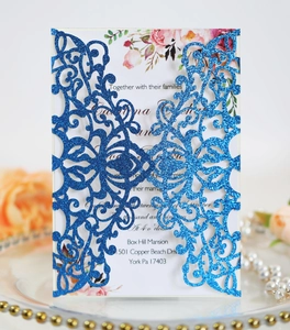 Close-up of laser-cut wedding invitation kit with blue glitter finish and floral details