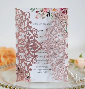 Macro shot of rose gold glitter laser-cut wedding invitation with elegant floral card