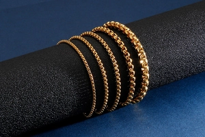Vue détaillée de cinq largeurs de bracelets en chaîne vénitienne dorée sur un support noir