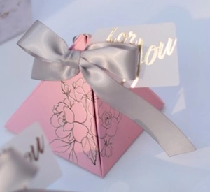 Macro shot of pink pyramid gift box with floral patterns and a grey satin bow