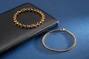 Macro detail of gold-plated stainless steel Rolo link chains with lobster clasps