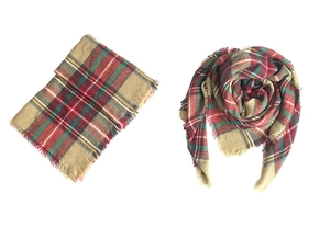 Detail view of red and green cashmere-like plaid scarf with fringed edges on white background