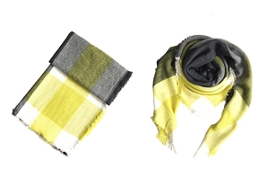 Detail of yellow and grey plaid scarf with fringe tassels on a clean white background