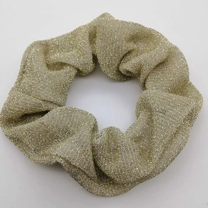 Sparkling champagne gold scrunchie with metallic glitter texture for stylish hair styling