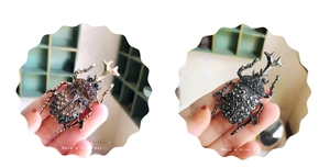 Detailed view of stag beetle brooches with vintage rhinestones in gold and black finish