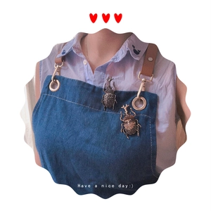 Detail of beetle brooches with crystals on a denim shirt collar showing intricate design