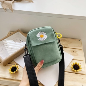 Close-up of green canvas mini bag featuring white daisy embroidery and adjustable strap