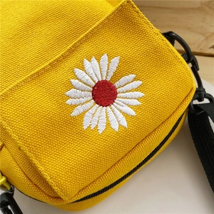 Close-up of yellow canvas crossbody bag featuring detailed daisy flower embroidery
