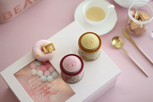 Detailed gift set featuring pink and gold tin tea canisters with a decorative donut box