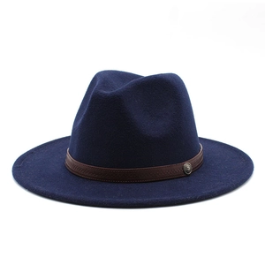 Detail of navy blue wool fedora hat with brown band and vintage metal badge ornament