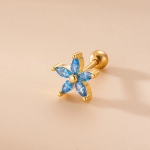Pendientes de flor dorados con piedras azules y cierre de rosca en fondo beige claro