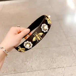 Detail of fabric headband with golden bees and crystal pearl flower embellishments