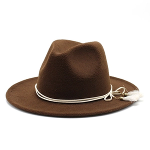 Detailed view of brown felt fedora hat featuring white tassel rope and gold metal accents