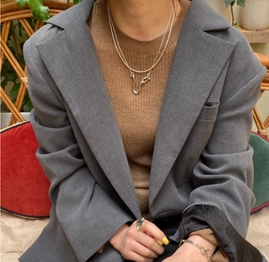 Close-up of layered silver necklace with U-shaped pendant on a grey suit jacket