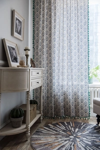 Detail of white curtain with blue geometric pattern and green tassel fringe decoration