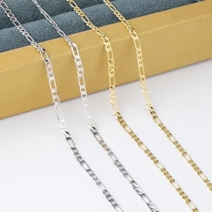 Close-up of 2.5mm gold and silver Cuban link chains draped over a yellow jewelry box