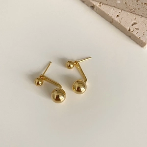 Detailed view of dual-ball gold stud earrings in S925 silver on minimalist stone decor