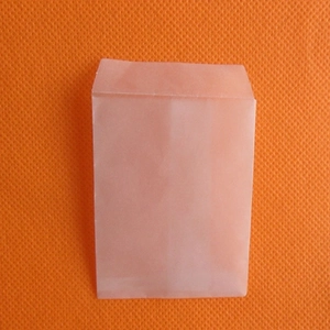 Translucent white tracing paper envelope for small jewelry storage on orange background