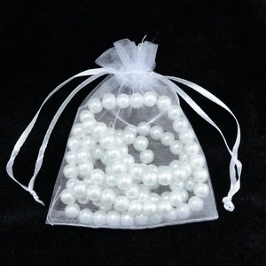 Detailed view of white organza drawstring gift bag filled with shiny imitation pearls