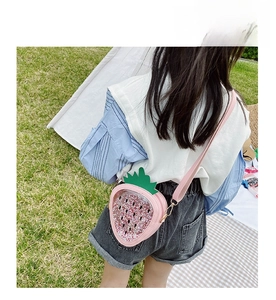 Detail of pink strawberry sequin crossbody bag with heart window for girls in outdoor setting