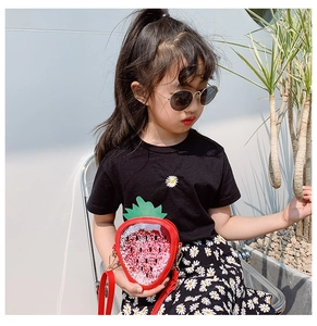 Outdoor shot of a girl wearing a bright red strawberry-shaped sequin crossbody bag