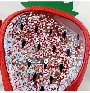Detail of red strawberry bag with sparkling star sequins and green leaf decoration