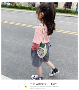 Detail of sequined strawberry crossbody bag with green leaf decor on a walking child