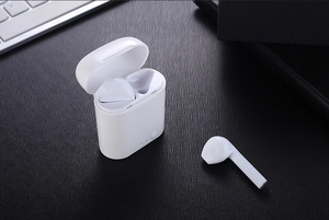Detalle de auriculares TWS blancos inalámbricos con estuche de carga en fondo oscuro