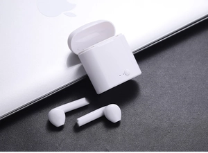 Detalle de auriculares inalámbricos i7mini blancos con estuche sobre fondo oscuro