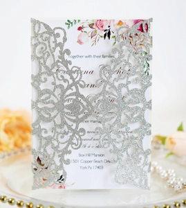 Macro shot of silver glitter laser-cut wedding invitation with elegant floral inner card