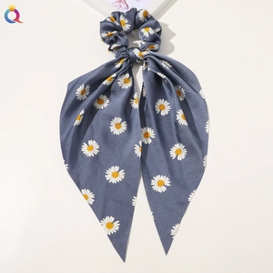Detail of blue-grey satin scrunchie scarf with white daisy floral pattern and silky texture