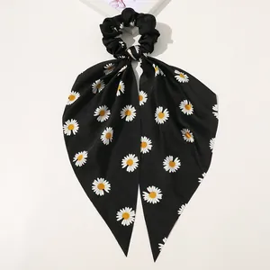 Detail of black satin hair scrunchie with long ribbons and white daisy floral print
