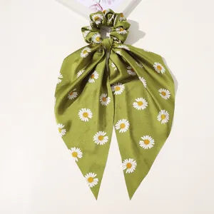 Detail of green satin ribbon hair scrunchie featuring white daisy floral pattern