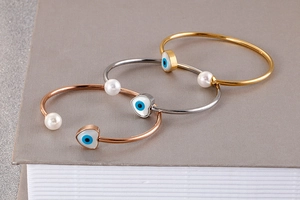 Detail of open bangles in gold and silver with pearl and heart evil eye charms