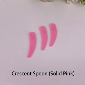 Three solid pink plastic crescent spoons for cosmetic cream and face mask application