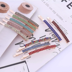Elegant rose gold metal bobby pins with colorful rhinestones on a magazine