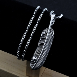 Detail of a vintage silver feather pendant with a small claw on a black velvet stand