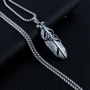 Polished stainless steel feather pendant necklace with skull motif on black background
