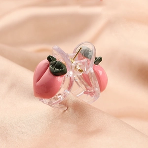 Macro detail of cute pink peach hair claw clips with green leaves on pink silk