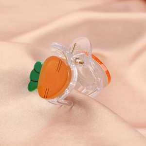 Close-up of cute carrot hair claw clip made of orange resin on silk background