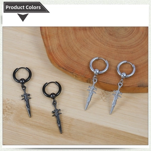 Detail view of gothic cross sword earrings in black and silver finishes on a wood tray