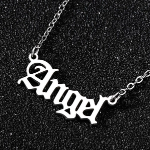 Macro detail of silver Angel pendant necklace with Gothic lettering on black sand background