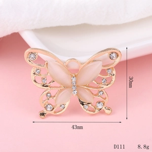Golden butterfly charm with white cat's eye stone and rhinestones, dimensions 43x30mm